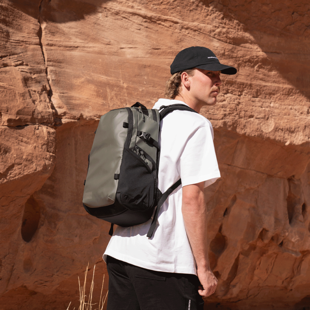 Man wearing the Green Stratus Photo 18L Backpack while hiking